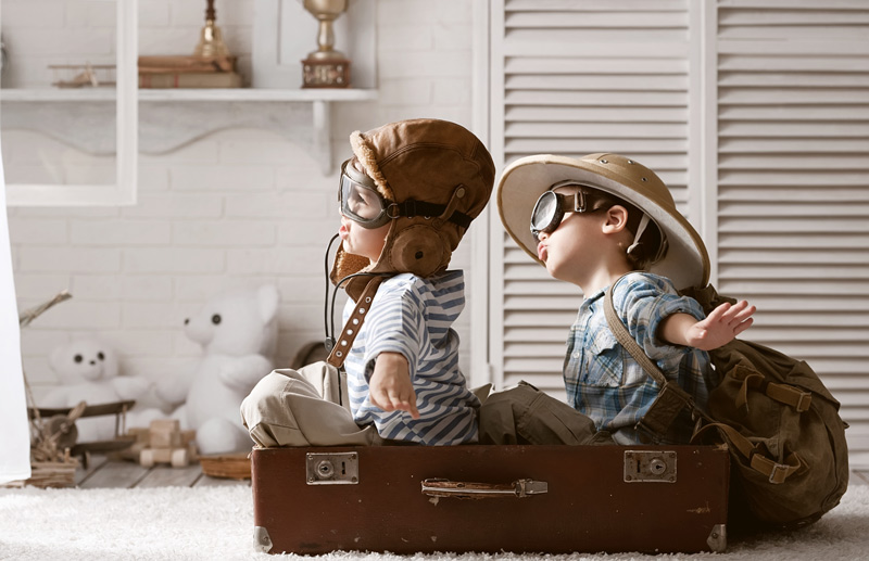 2 kids pretending to fly in a briefcase